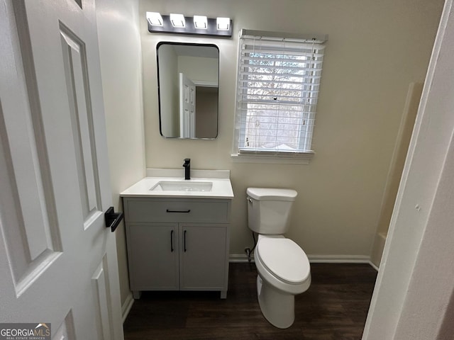 bathroom featuring toilet, baseboards, wood finished floors, and vanity