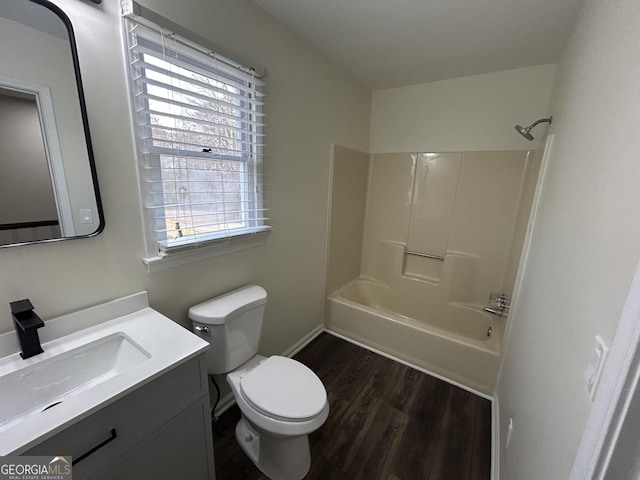 bathroom with toilet, vanity, shower / tub combination, wood finished floors, and baseboards