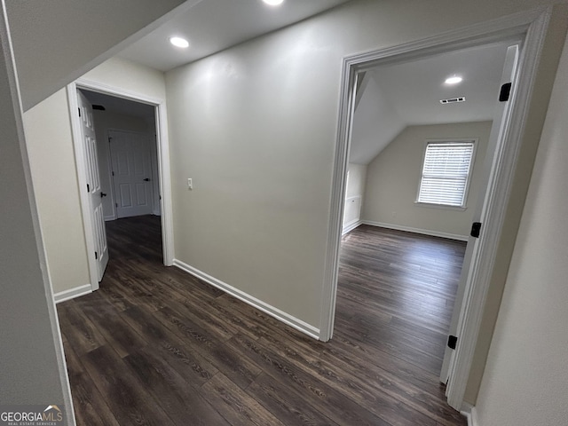 hall featuring vaulted ceiling, visible vents, dark wood finished floors, and baseboards