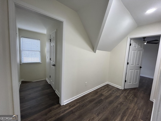 corridor with lofted ceiling, dark wood-style flooring, and baseboards