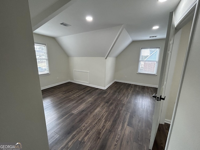 additional living space with lofted ceiling, a wealth of natural light, dark wood-type flooring, and visible vents