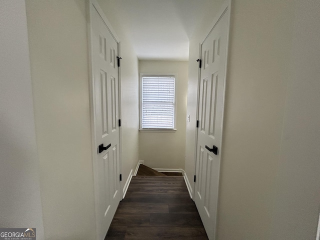 hall featuring dark wood-style flooring and baseboards