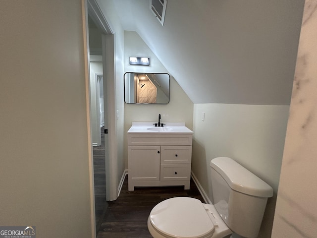 half bath with lofted ceiling, toilet, wood finished floors, vanity, and baseboards