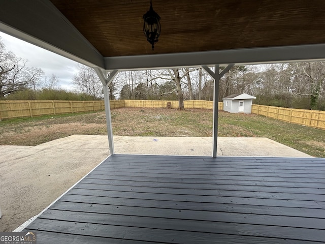 wooden terrace featuring an outbuilding, a storage unit, a patio area, and a fenced backyard