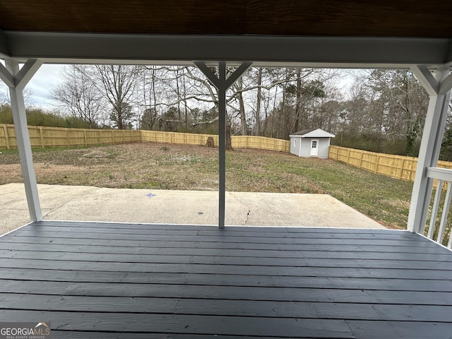 wooden deck featuring a patio area, a fenced backyard, a storage unit, and an outdoor structure