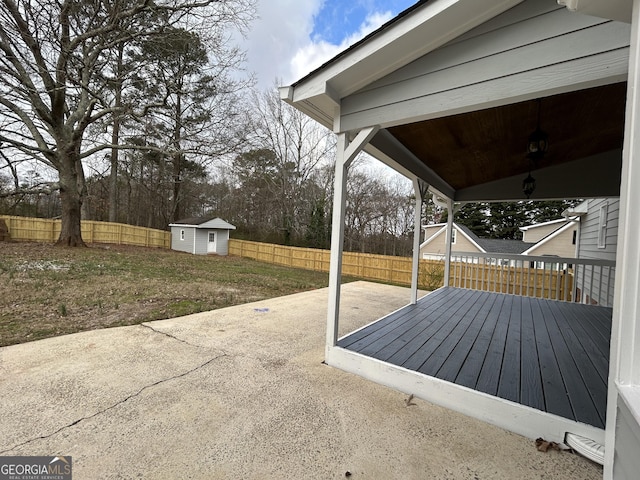 view of patio / terrace with a fenced backyard, a storage unit, and an outbuilding