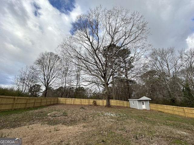 view of yard with a fenced backyard, an outdoor structure, and a storage unit