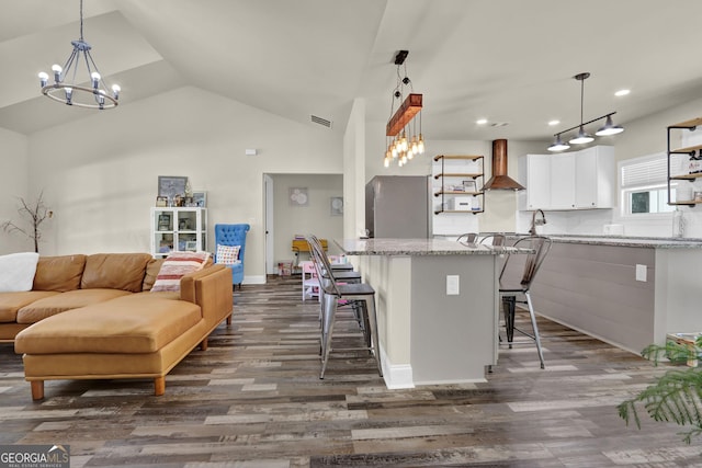 90 Jefferson Rd, Statham, GA 30666 - kitchen featuring wall chimney range hood, a kitchen breakfast bar, white cabinetry, dark wood-style flooring, and freestanding refrigerator