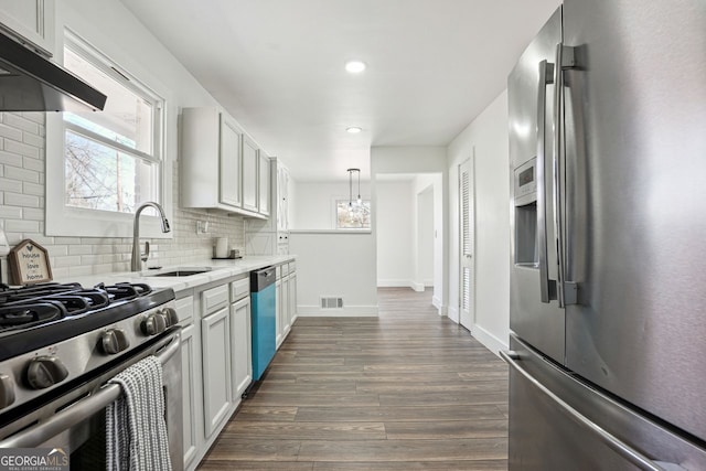 kitchen featuring under cabinet range hood, a sink, visible vents, appliances with stainless steel finishes, and dark wood finished floors