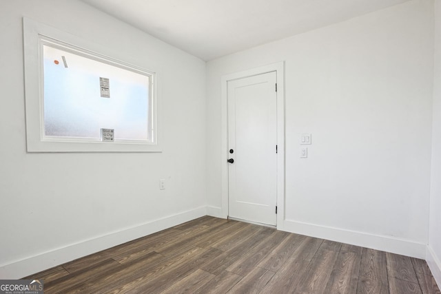 unfurnished room with baseboards and dark wood finished floors