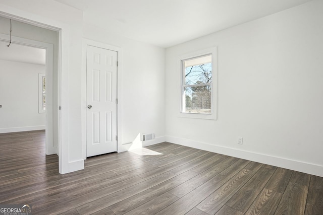 unfurnished bedroom featuring dark wood-style flooring, visible vents, and baseboards