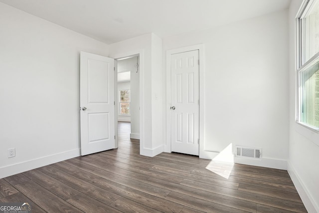 unfurnished bedroom featuring dark wood finished floors, visible vents, and baseboards