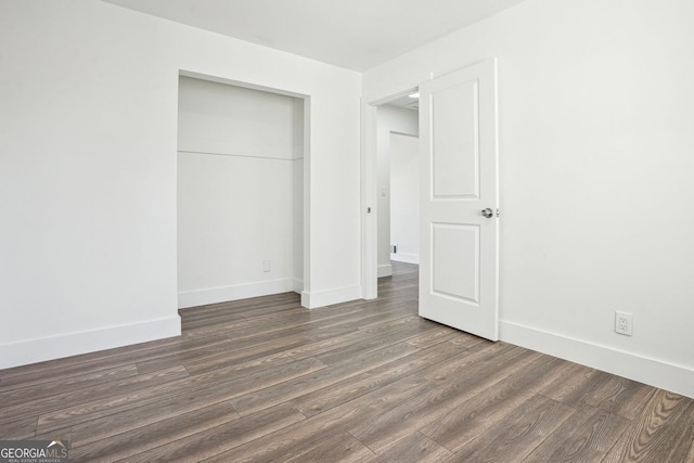 unfurnished bedroom with a closet, baseboards, and wood finished floors