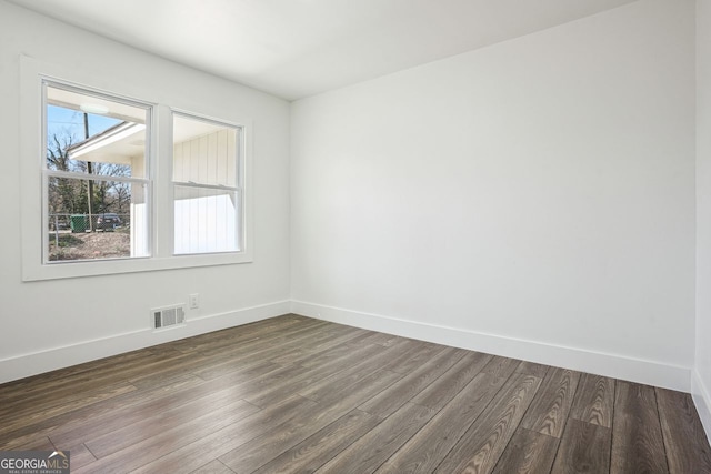 unfurnished room featuring dark wood-style floors, visible vents, and baseboards