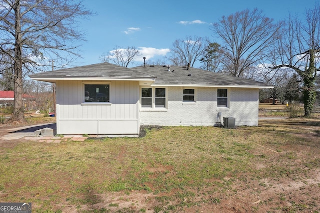 rear view of property with a yard, brick siding, and cooling unit