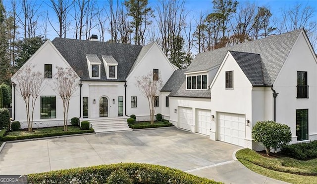 view of front of house featuring stucco siding, driveway, a chimney, and a garage