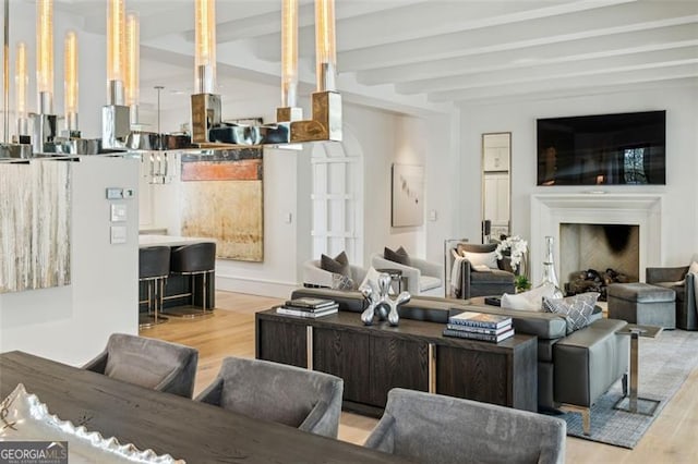 living area featuring beam ceiling, wood finished floors, and a fireplace