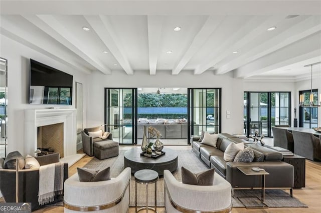 living room with beam ceiling, light wood-style flooring, recessed lighting, and a fireplace with raised hearth