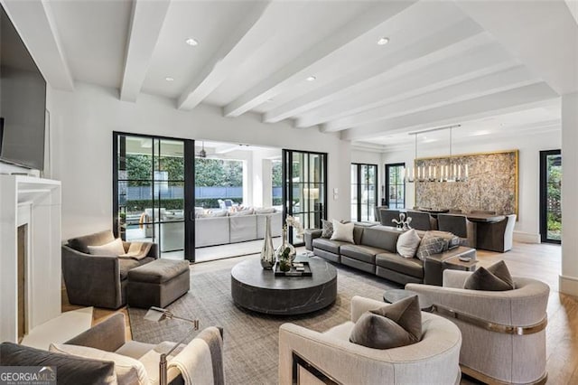 living area with recessed lighting, beam ceiling, a healthy amount of sunlight, and wood finished floors