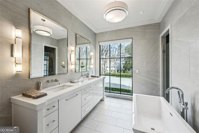 bathroom with a sink, a freestanding tub, tile walls, and ornamental molding