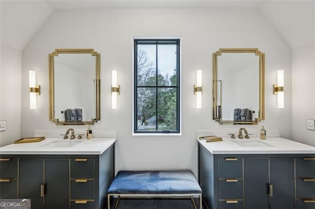 bathroom featuring two vanities, lofted ceiling, and a sink