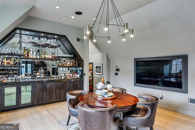 dining space featuring vaulted ceiling, bar area, wood finished floors, and visible vents