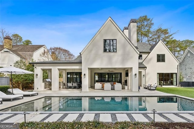 back of property featuring an outdoor living space, stucco siding, a chimney, and a patio area