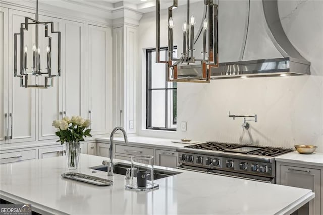 kitchen featuring wall chimney range hood, double oven range, pendant lighting, decorative backsplash, and a sink