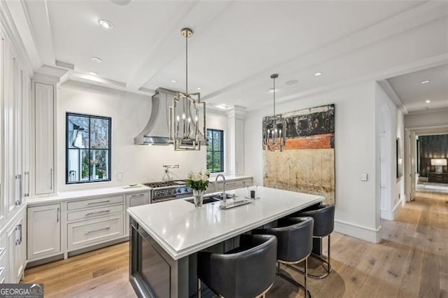 kitchen with light wood-style flooring, stainless steel range, light countertops, and wall chimney exhaust hood