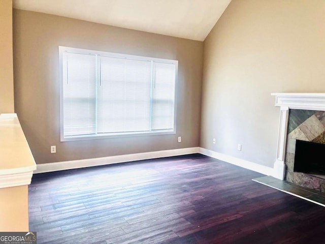 unfurnished living room featuring vaulted ceiling, a fireplace, wood finished floors, and baseboards