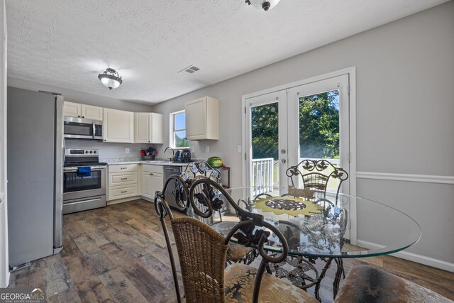 kitchen featuring stainless steel appliances, a sink, dark wood-style floors, white cabinetry, and a textured ceiling