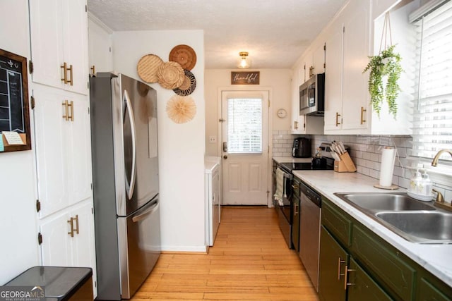 kitchen featuring light wood-type flooring, white cabinetry, stainless steel appliances, and a sink