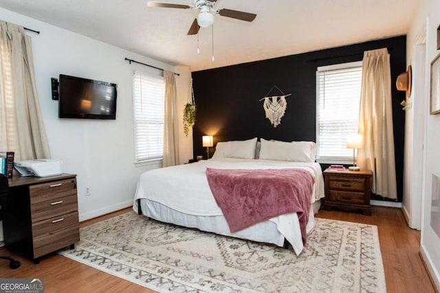 bedroom featuring multiple windows, baseboards, and wood finished floors