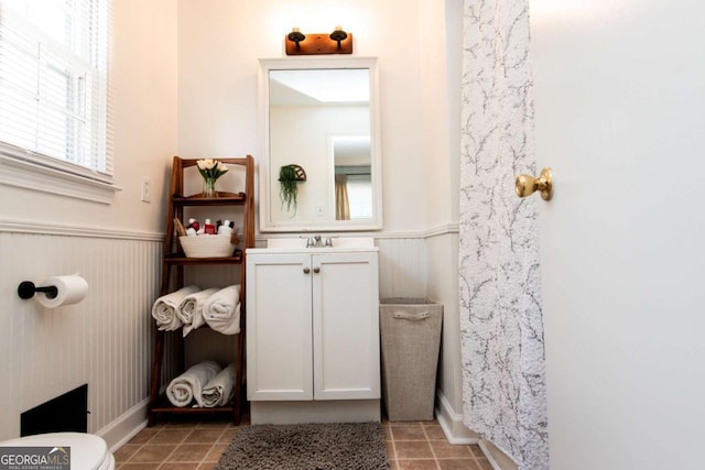 bathroom with toilet, wainscoting, vanity, and tile patterned floors