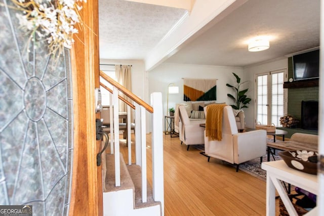 living room featuring stairway, ornamental molding, wood finished floors, french doors, and a fireplace