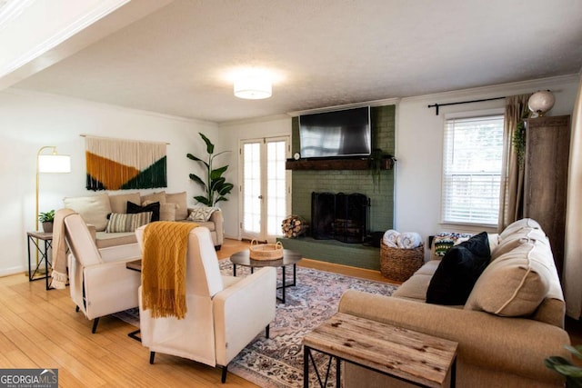 living area with a fireplace, plenty of natural light, wood finished floors, and crown molding