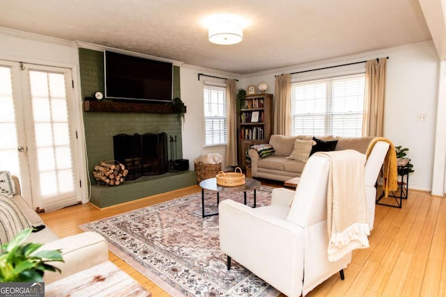 living room with light wood-type flooring, a brick fireplace, and crown molding