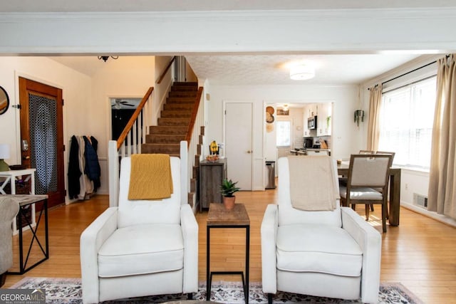 interior space with light wood finished floors, stairway, visible vents, and crown molding