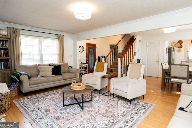 living room with light wood-style floors, a textured ceiling, stairway, and crown molding