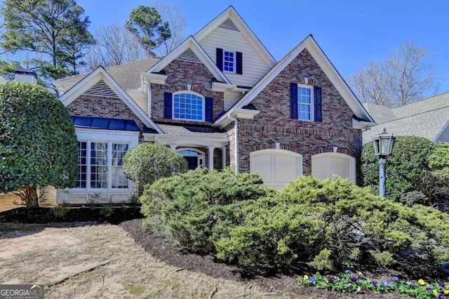 view of front facade featuring a garage, a shingled roof, and brick siding