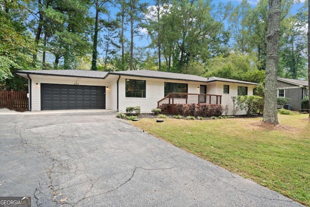 ranch-style house featuring a garage, driveway, fence, a front yard, and brick siding