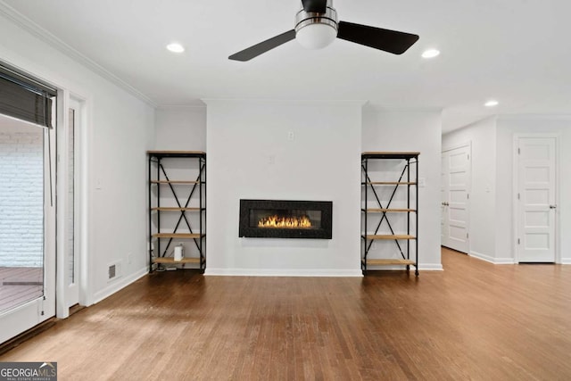 unfurnished living room with baseboards, a glass covered fireplace, ornamental molding, wood finished floors, and recessed lighting