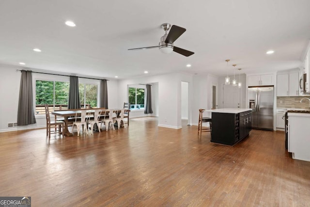 kitchen with white cabinets, appliances with stainless steel finishes, a center island, dark wood-style floors, and tasteful backsplash