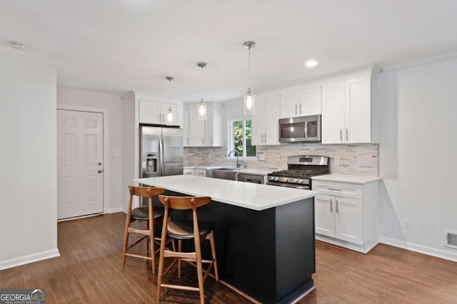 kitchen featuring stainless steel appliances, tasteful backsplash, light countertops, white cabinets, and a kitchen breakfast bar