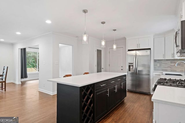 kitchen featuring crown molding, stainless steel appliances, tasteful backsplash, light countertops, and a sink