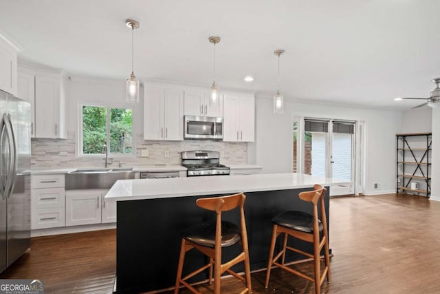 kitchen with light countertops, appliances with stainless steel finishes, a sink, and white cabinetry