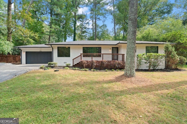 view of front of house featuring an attached garage, brick siding, fence, driveway, and a front lawn