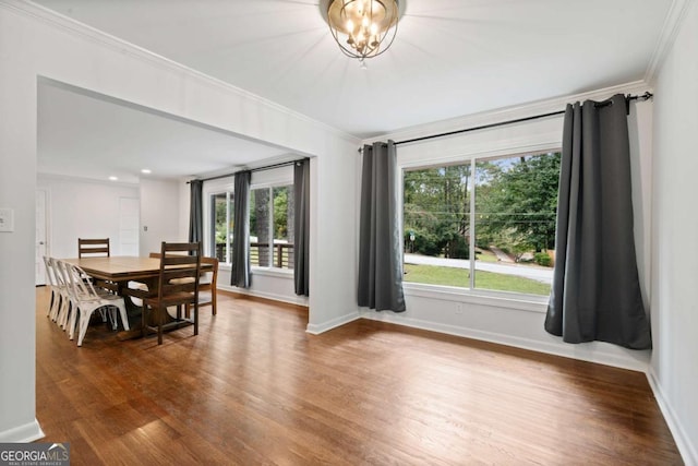 dining area with baseboards, an inviting chandelier, wood finished floors, and crown molding