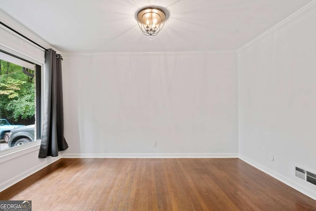 spare room with visible vents, crown molding, baseboards, and wood finished floors