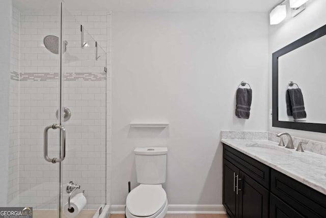 bathroom featuring toilet, a stall shower, baseboards, and vanity